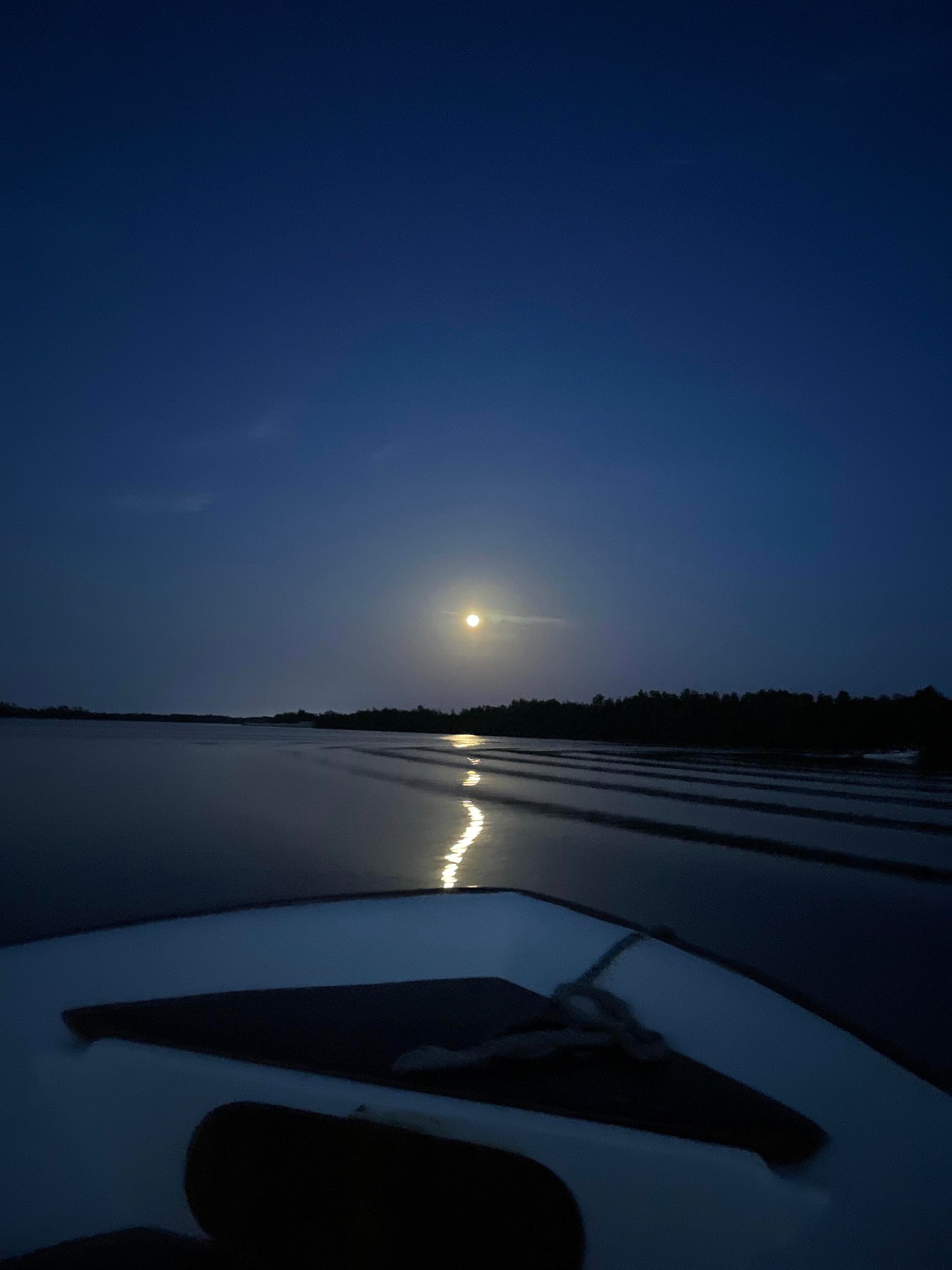 Moonlit wake from a boat bow at dusk