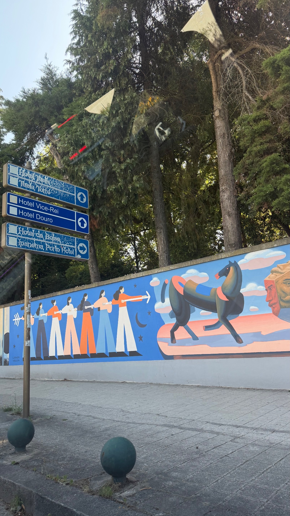 Weathered blue hotel signs beside a mural in Porto